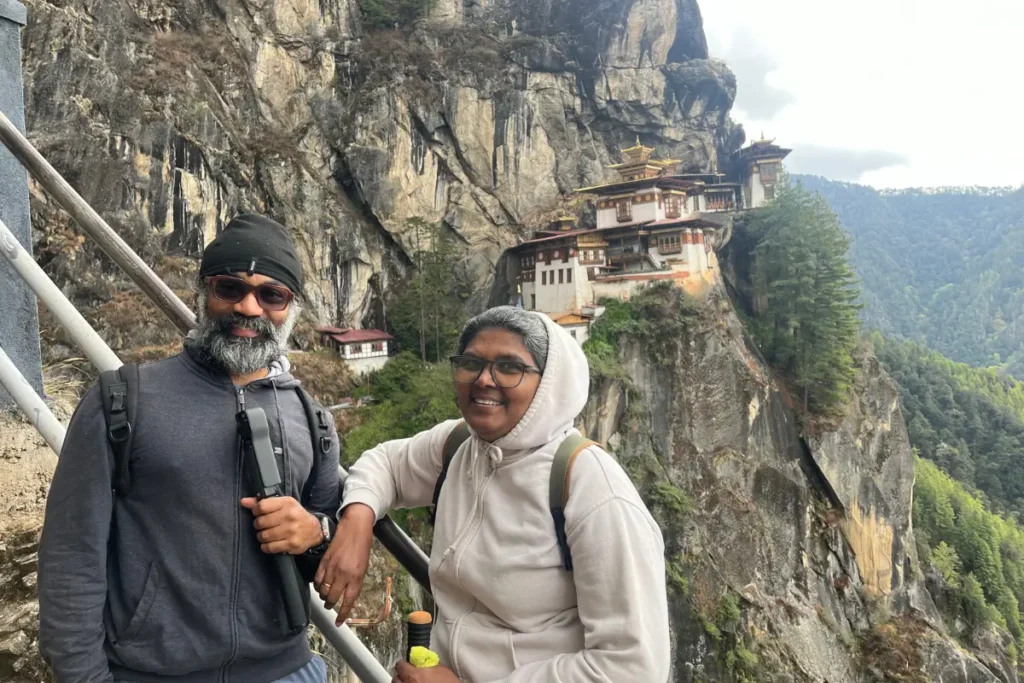 Kishore and Lakshmi, a lovely couple from Kerala, India, smile for a photo at the stunning viewpoint overlooking Taktsang Monastery.
