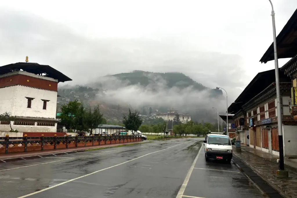 Quiet rainy morning on the streets of Paro, Bhutan, with misty mountains and Paro Dzong in the background.
