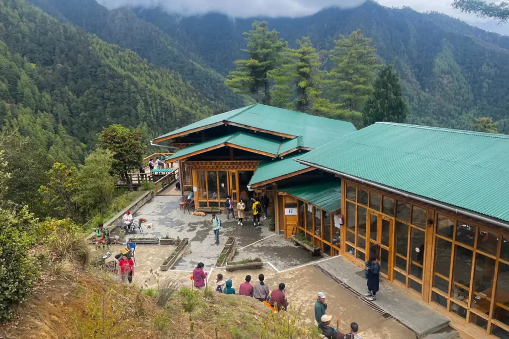 Taktsang Cafeteria on the Tiger’s Nest Monastery hiking trail in Bhutan, surrounded by lush green forest and mountains, with trekkers resting and enjoying the scenic view.