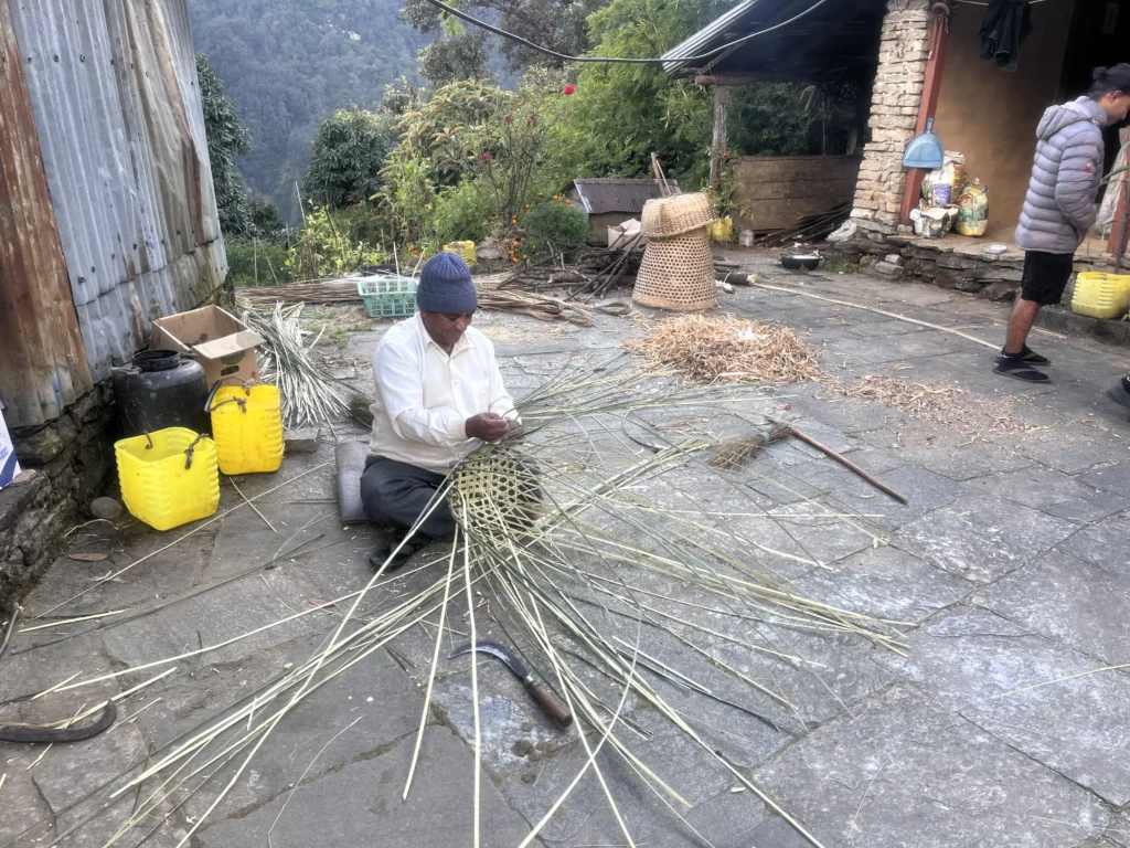 Man weaving a bamboo basket in a rural courtyard